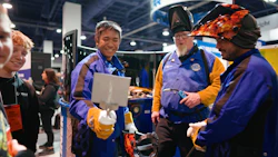 Team members in blue and yellow jackets collaborating at technical conference