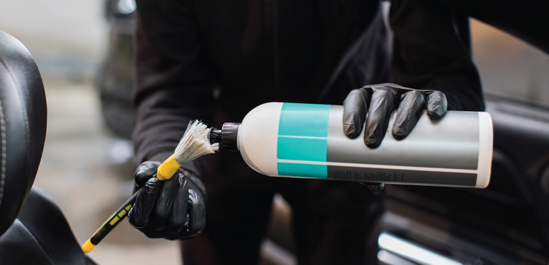 Gloved hand holding cleaning or automotive product bottle