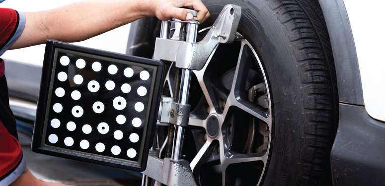 Wheel alignment sensor mounted on car tire during automotive diagnostic procedure