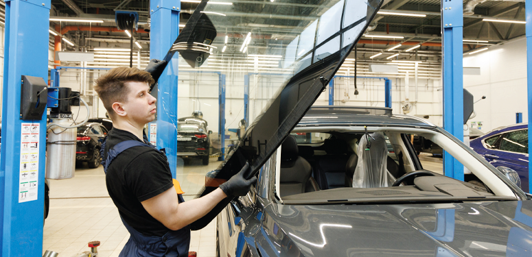 Auto technician lifting car hood in blue service center workshop