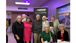 Group of six older adults posing near CarStar automotive service logo