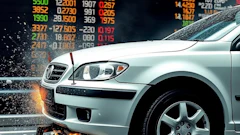 Silver car with financial stock market data in background, showing dynamic motion