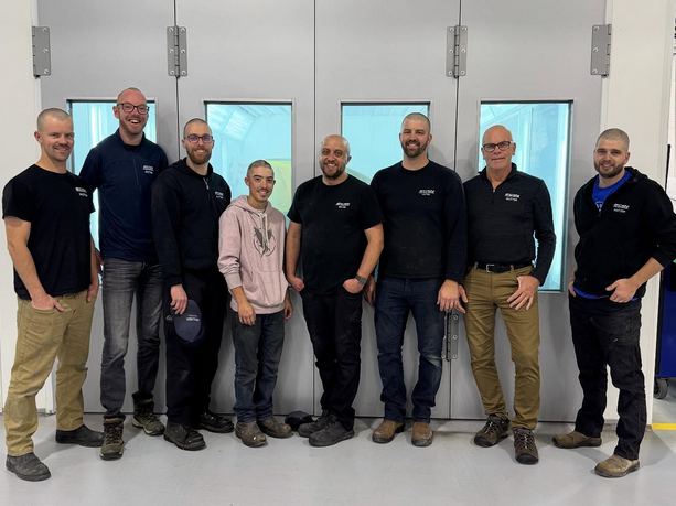 Team of seven professionals standing together in an industrial workspace