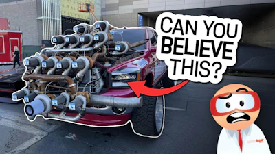 Customized red vehicle with multiple blue exhaust pipes in urban setting