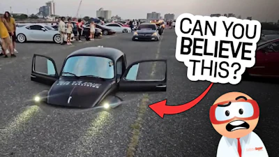 Lowered black car with doors open at automotive event with other vehicles in background