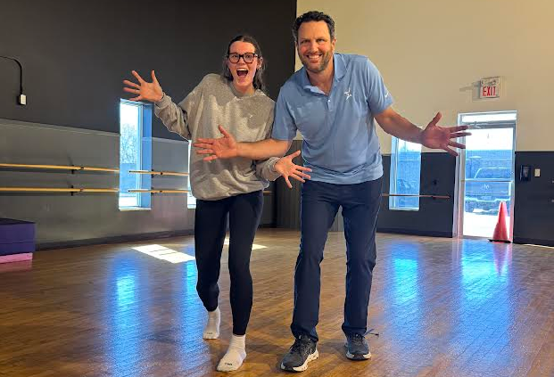 Two enthusiastic people gesturing with open arms in a dance studio