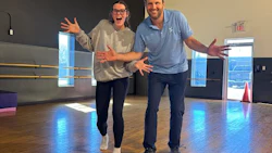 Two enthusiastic people gesturing with open arms in a dance studio
