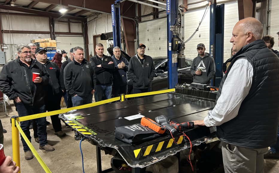 Automotive technicians gathered around workbench in industrial repair shop