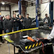 Automotive technicians gathered around workbench in industrial repair shop
