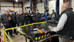 Automotive technicians gathered around workbench in industrial repair shop