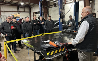 Automotive technicians gathered around workbench in industrial repair shop