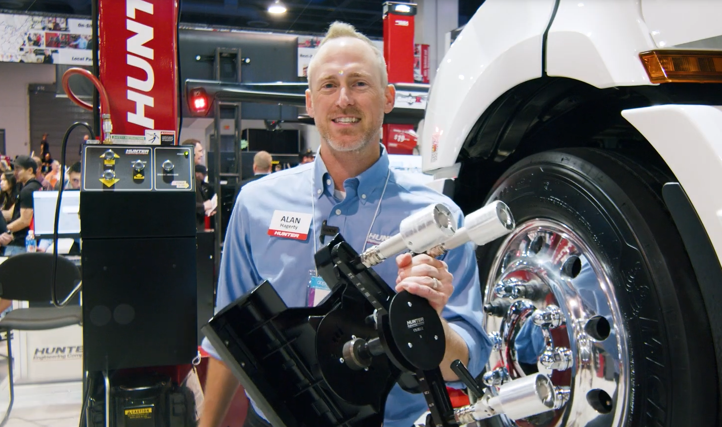 Smiling technician with tire mounting equipment at automotive industry trade show
