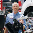 Smiling technician with tire mounting equipment at automotive industry trade show
