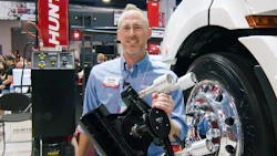 Smiling technician with tire mounting equipment at automotive industry trade show