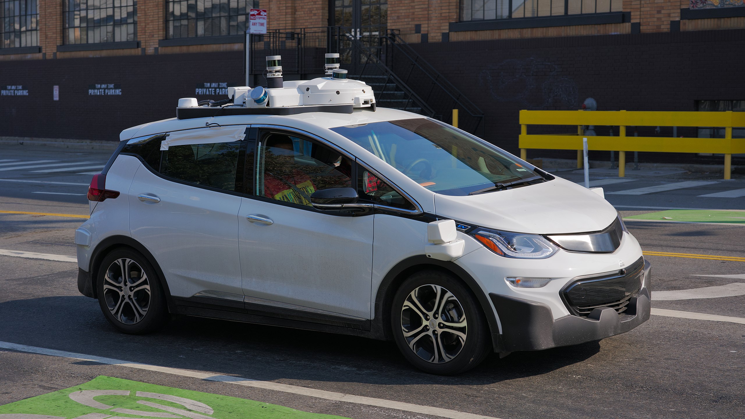 White self-driving Chevrolet Bolt electric vehicle with roof sensors in urban parking lot