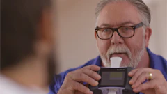 Older man with glasses carefully examining a handheld electronic device