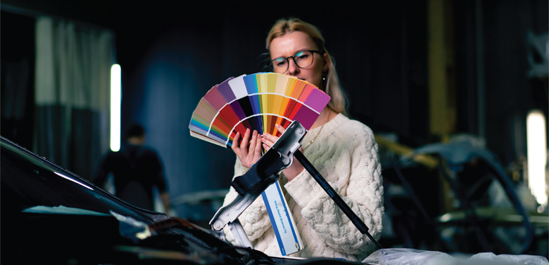 Designer reviewing color palette near automotive equipment in workshop