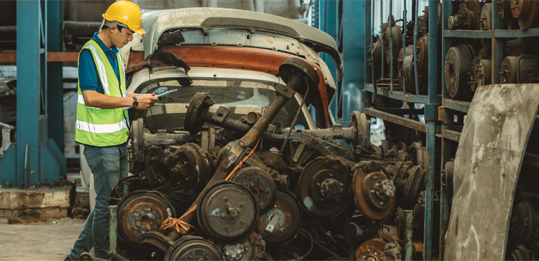 Worker in safety vest inspecting automotive parts in industrial warehouse