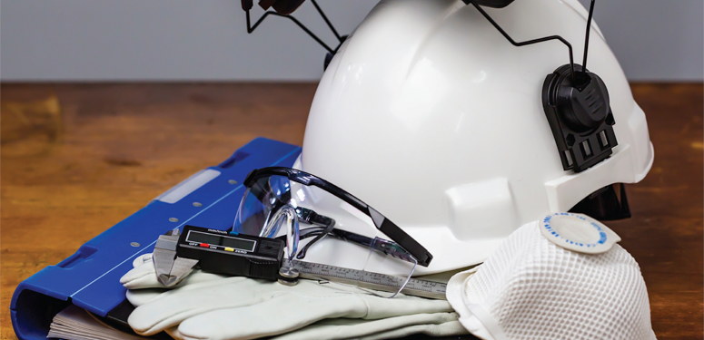 White safety helmet, protective gloves, and work tools on wooden surface