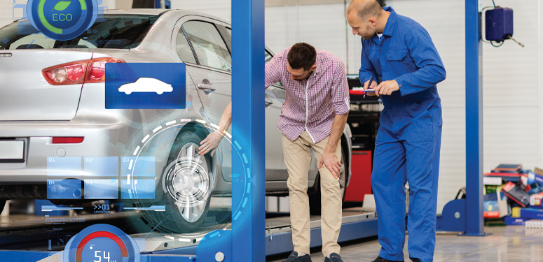 Automotive technician examining car wheel on lift in repair shop