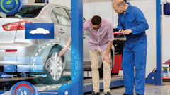 Automotive technician examining car wheel on lift in repair shop