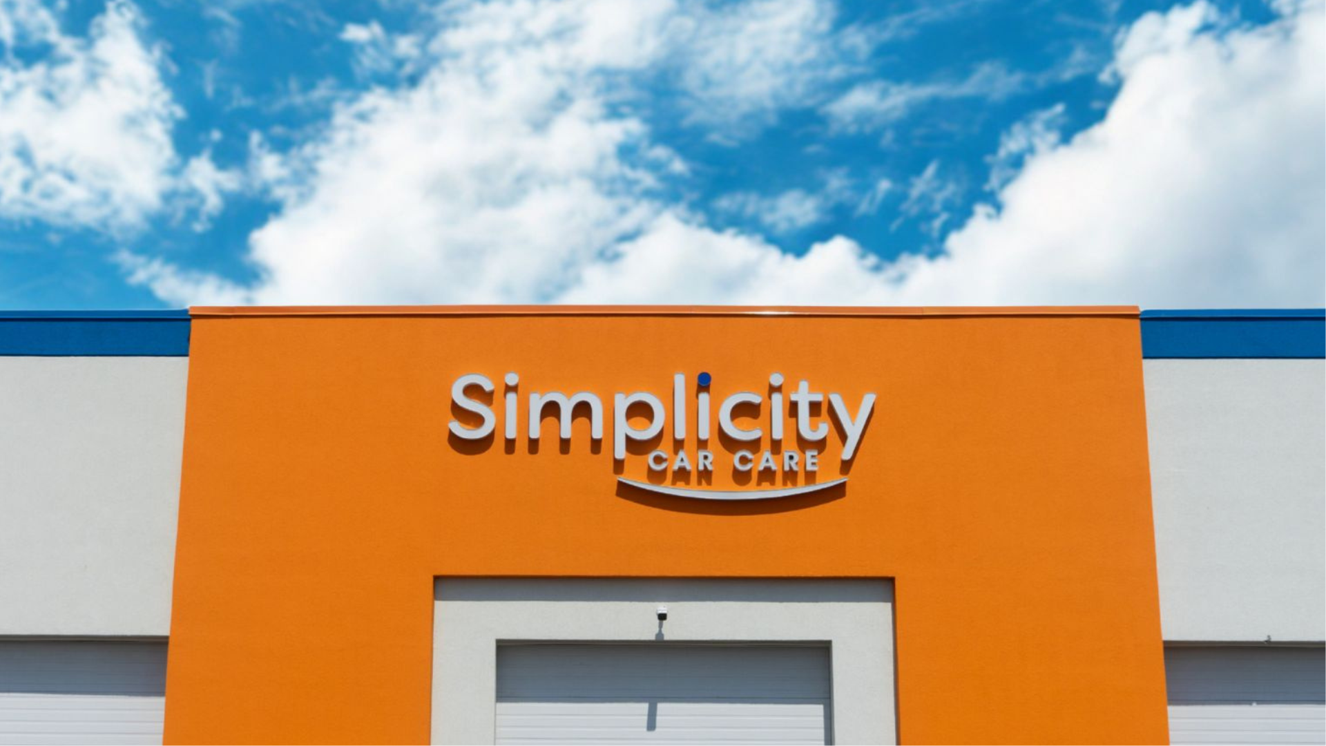 Simplicity Car Care logo on bright orange building exterior
