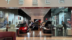 Tesla showroom interior with red and black electric vehicles on display