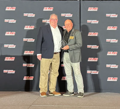 Two men receiving award at SEMA industry event with branded backdrop