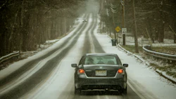 Gray Honda sedan driving on snowy, winding forest road with speed limit sign