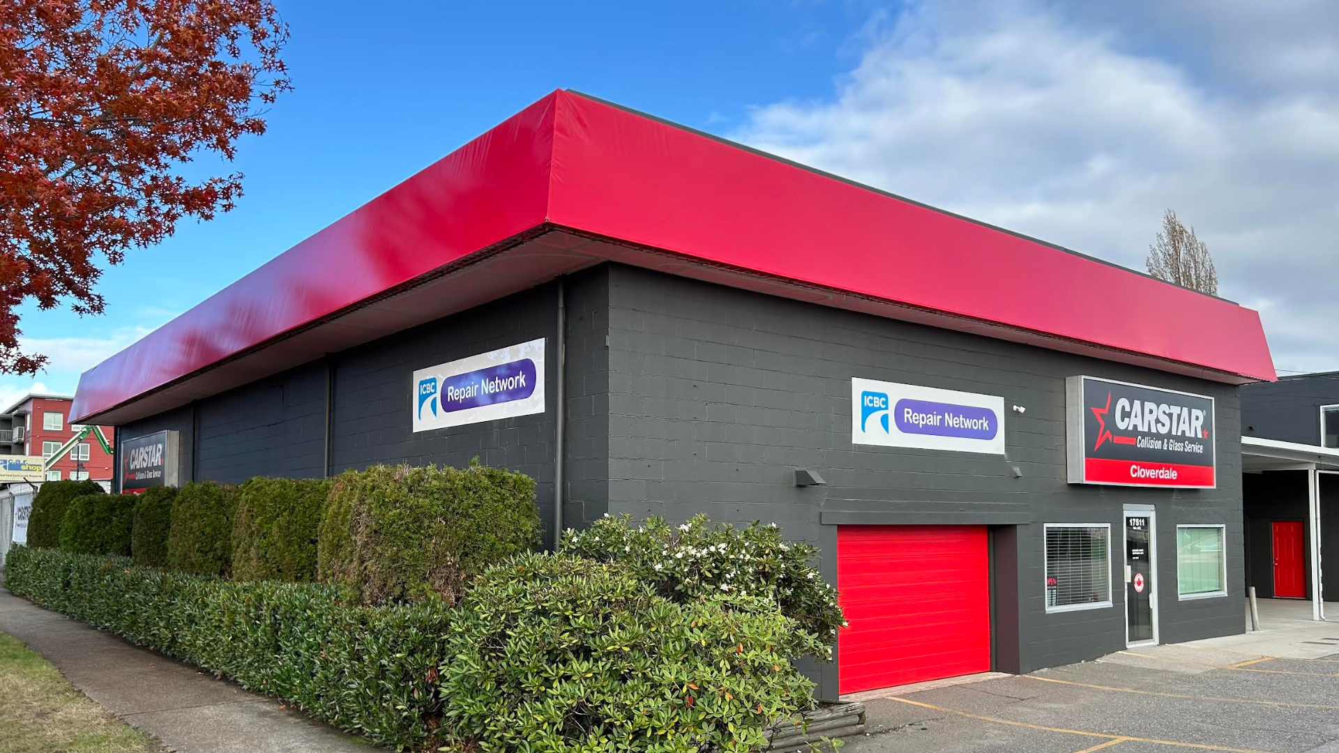 Gray commercial building with red roof, Repair Network and Carstar signs