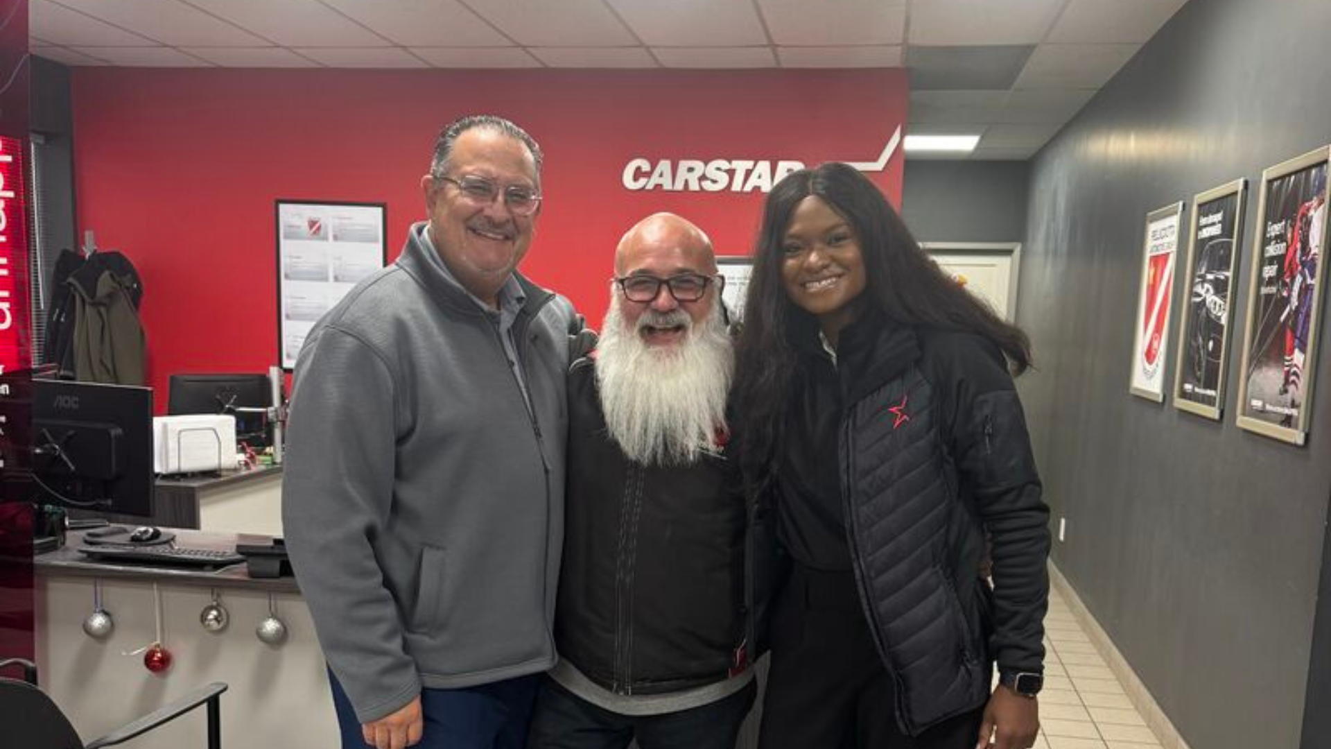 Three people posing in Carstar automotive service center with red branding