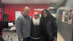 Three people posing in Carstar automotive service center with red branding
