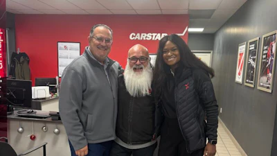 Three people posing in Carstar automotive service center with red branding