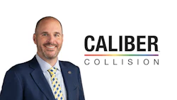 Smiling professional in navy suit with Caliber Collision corporate logo