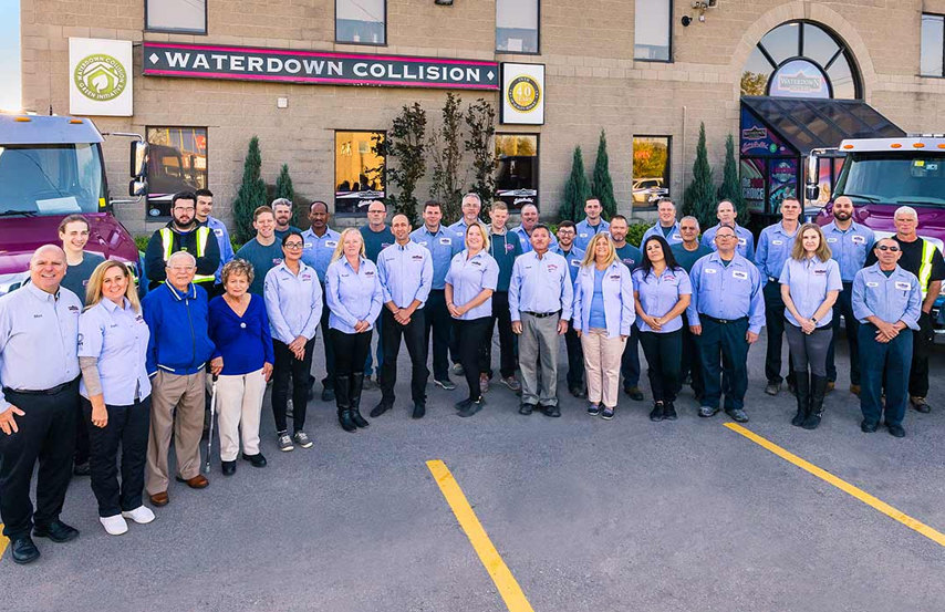 Large team of auto repair technicians posing outside Waterdown Collision shop