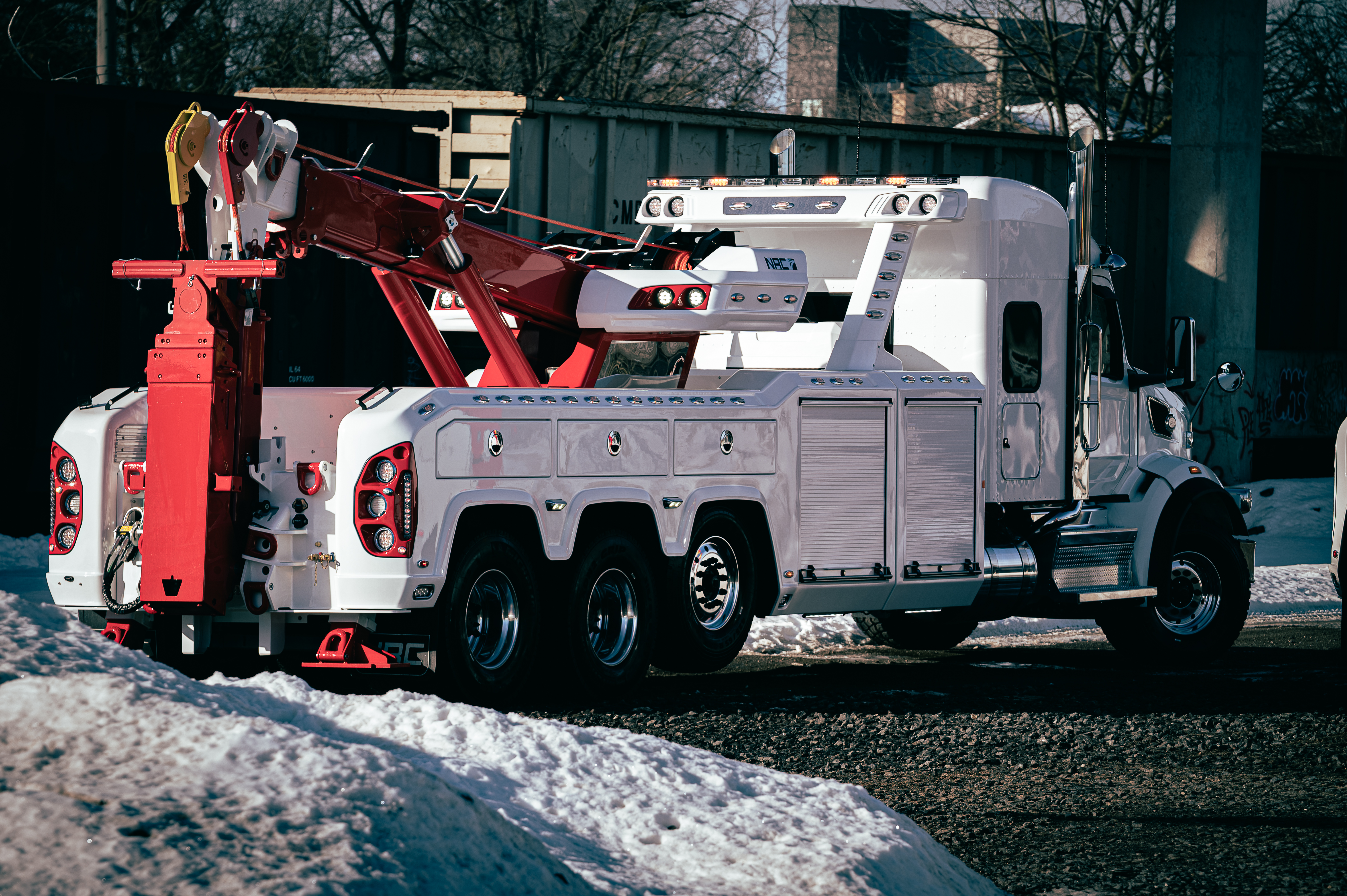 White and red heavy-duty tow truck parked on snowy ground near trees