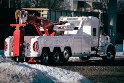 White and red heavy-duty tow truck parked on snowy ground near trees
