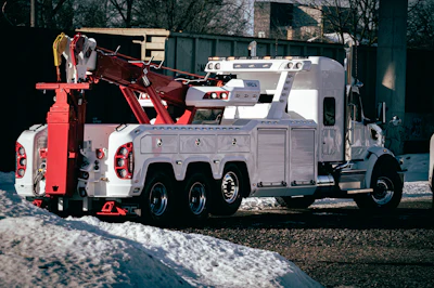 White and red heavy-duty tow truck parked on snowy ground near trees