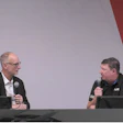 Two professionals discussing on stage with microphones
