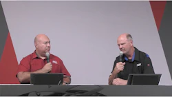 Two presenters speaking at a conference with microphones and dark background