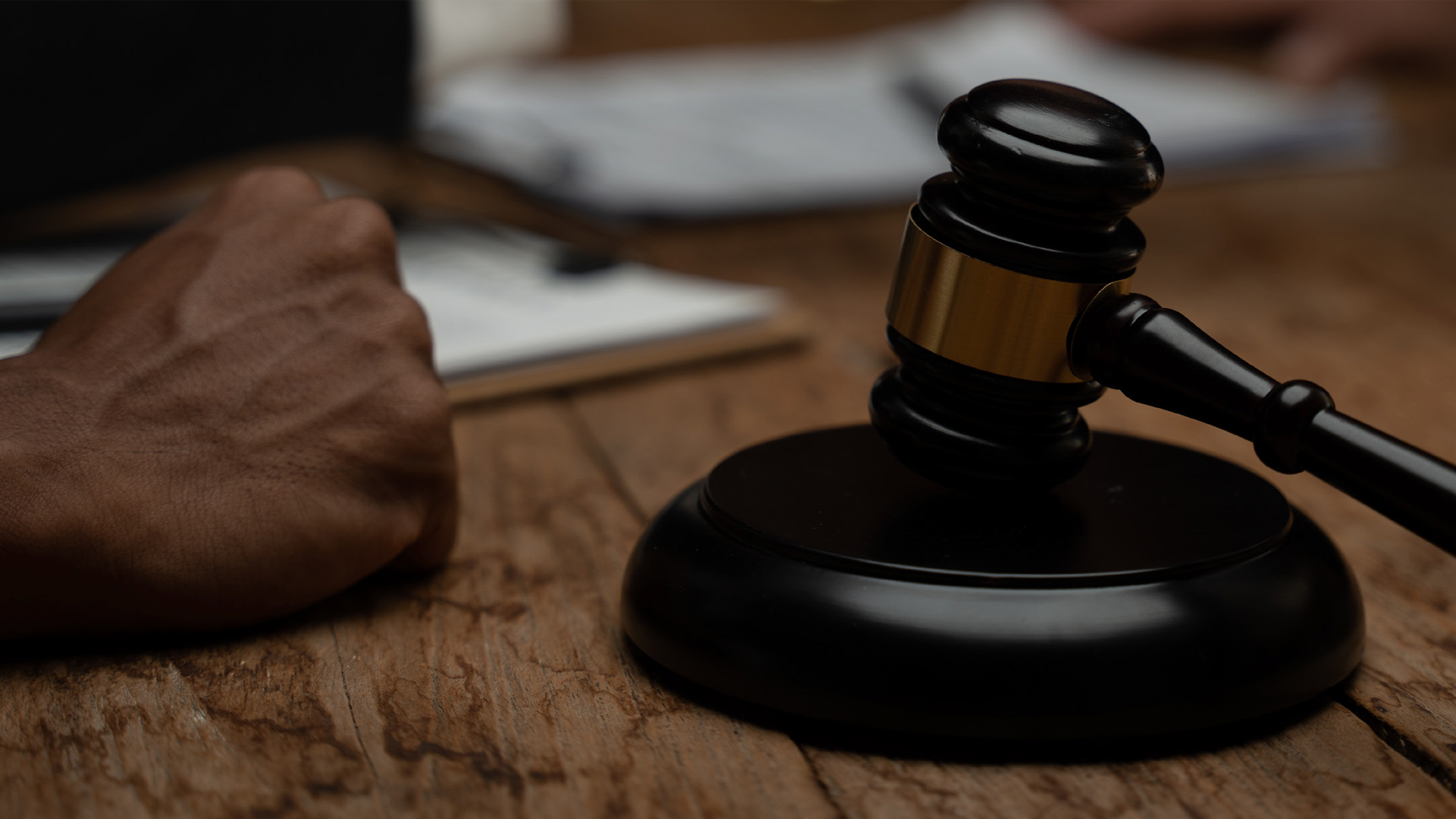 Black wooden gavel on sound block near legal document