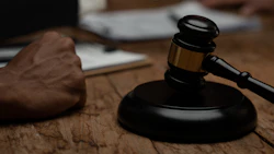 Black wooden gavel on sound block near legal document