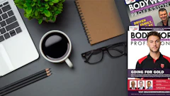 Workspace desk with laptop, coffee, magazines, and office accessories