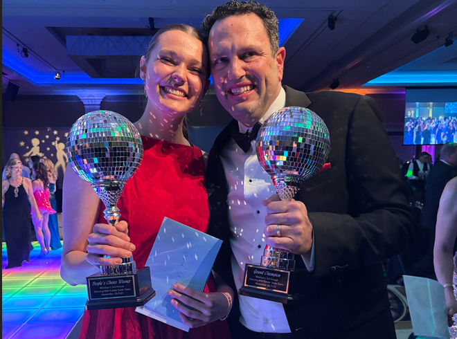 Two dancers holding disco ball trophies at an elegant event