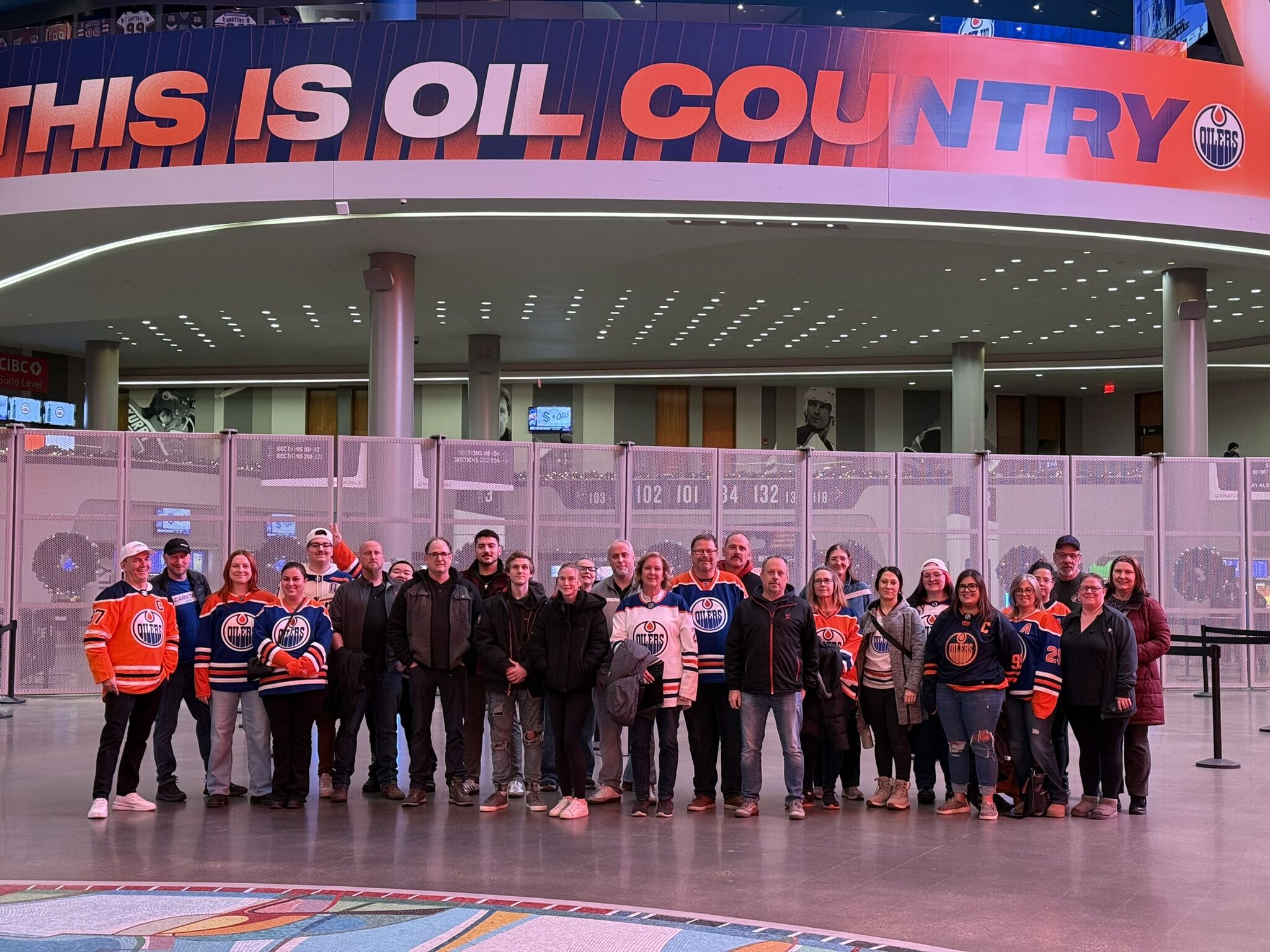 Group of Edmonton Oilers fans posing in arena concourse under 'This is Oil Country' sign