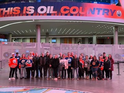 Group of Edmonton Oilers fans posing in arena concourse under 'This is Oil Country' sign