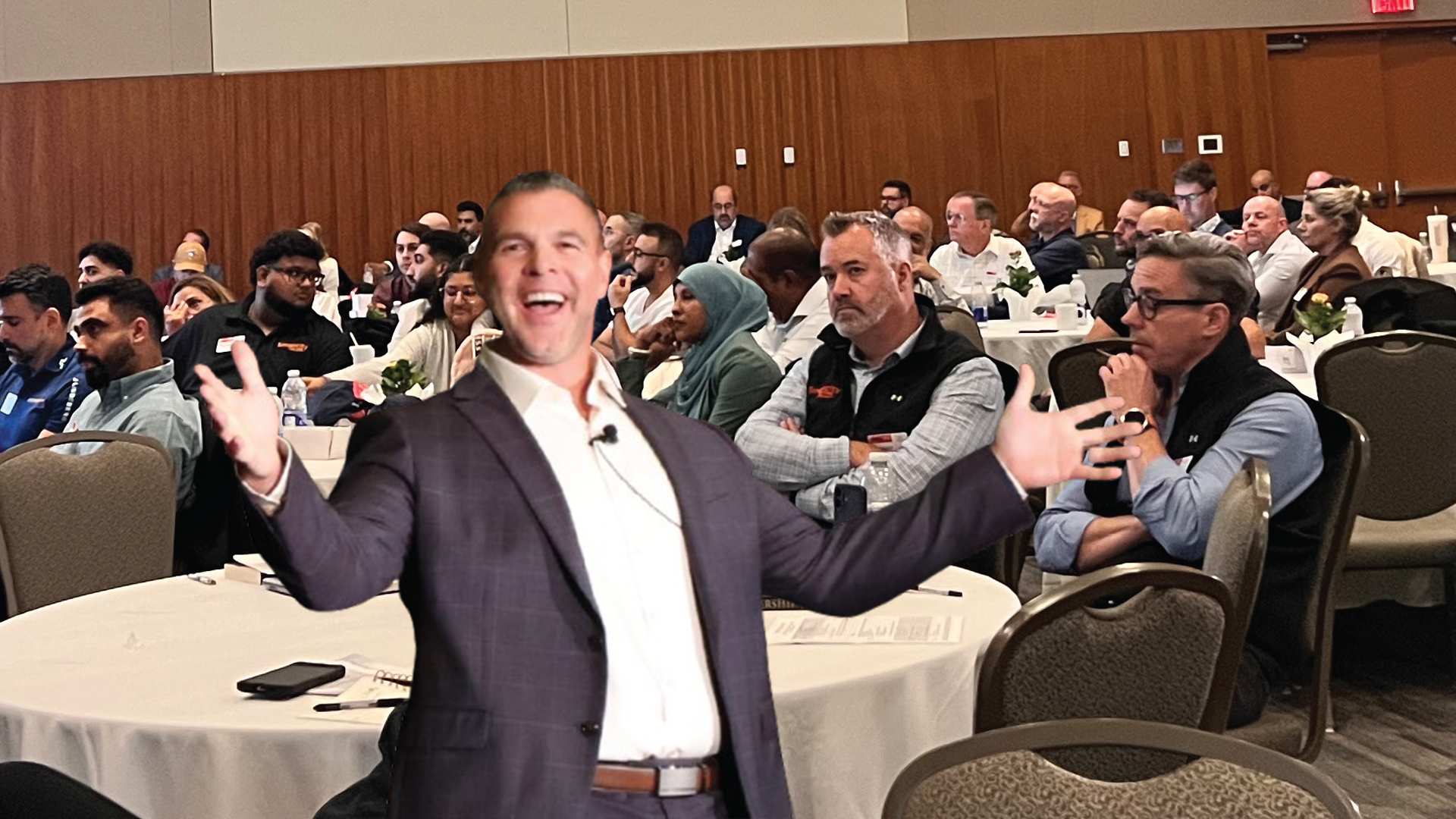 Energetic speaker presenting at business conference with audience in background