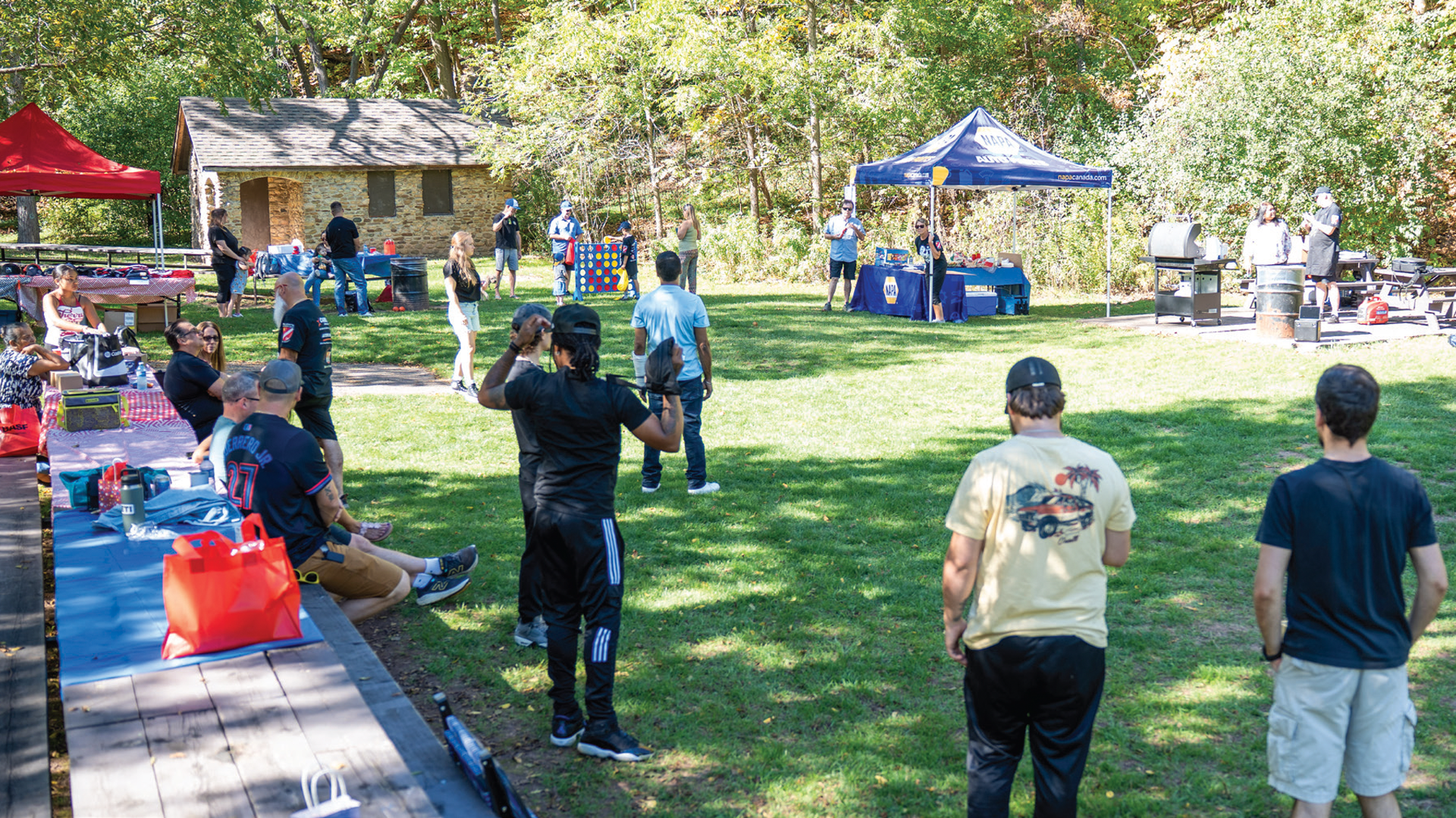 Community outdoor event with blue and red tents on grassy park grounds