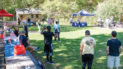 Community outdoor event with blue and red tents on grassy park grounds