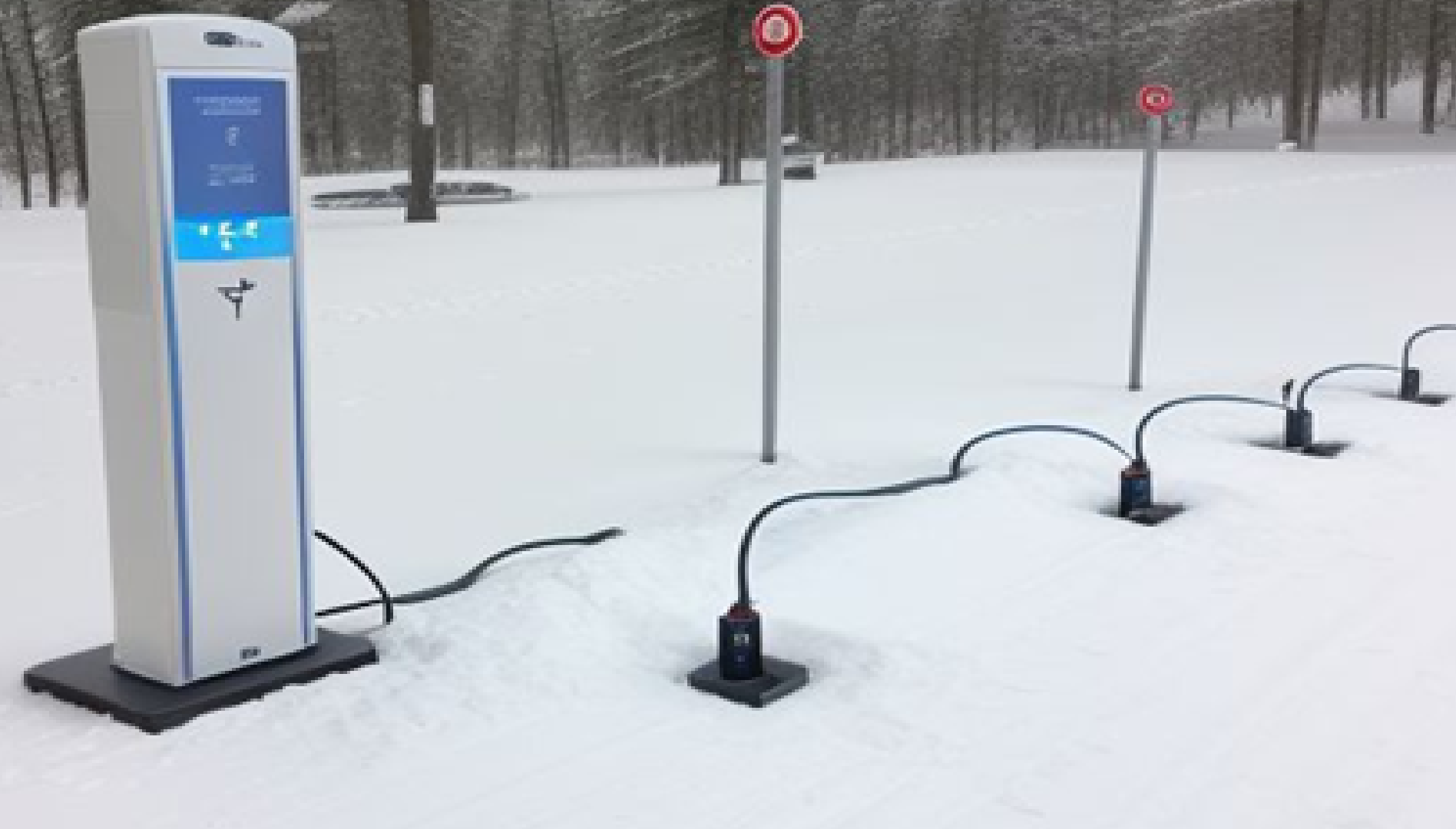 Electric vehicle charging station with power outlets in snow-covered winter landscape
